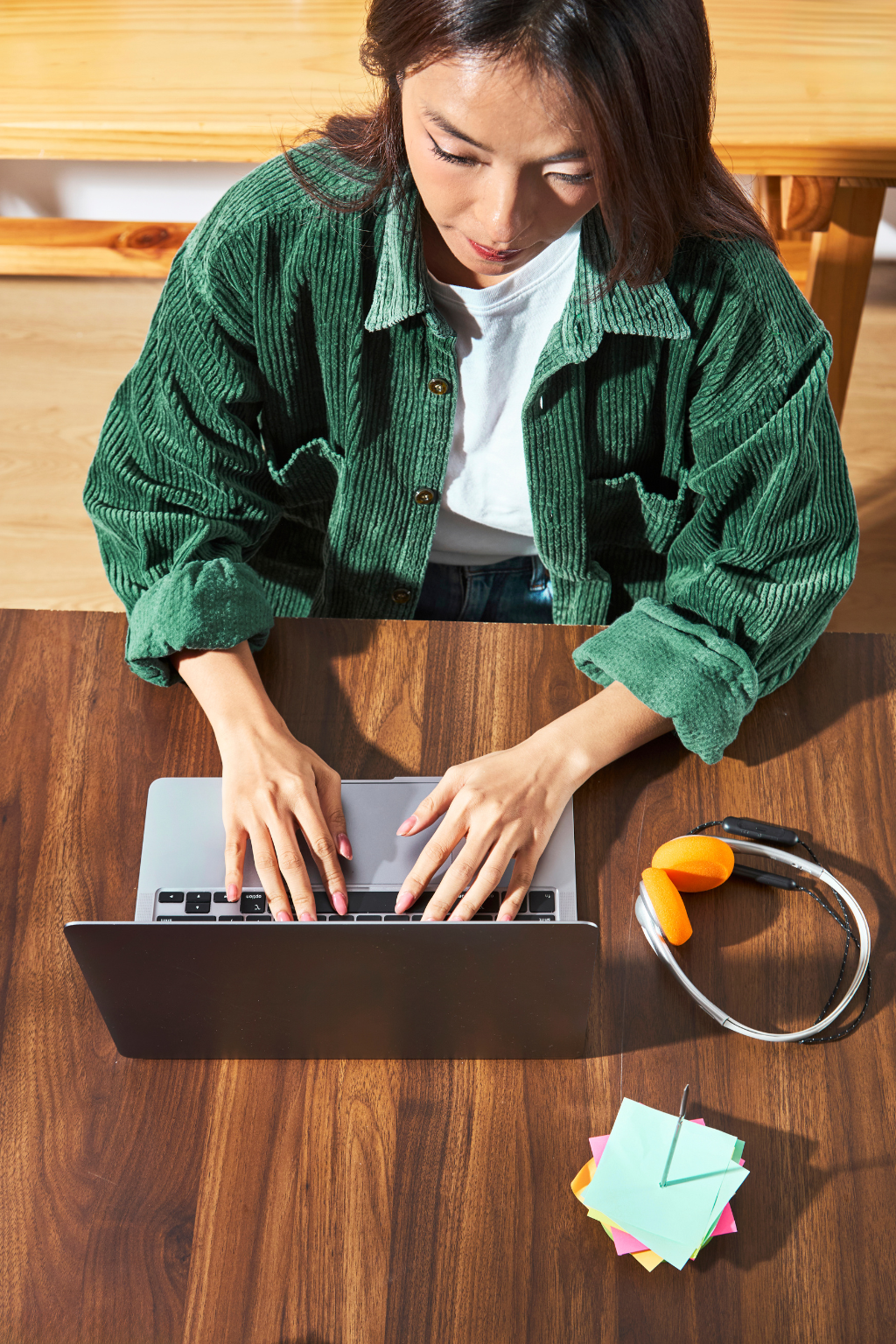 Kobieta pracująca przy laptopie podczas szkolenia live, ze słuchawkami i notatkami na biurku